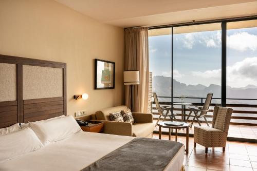 Una habitación de hotel con una cama, una mesa y sillas. en Parador de Cruz de Tejeda, en Tejeda
