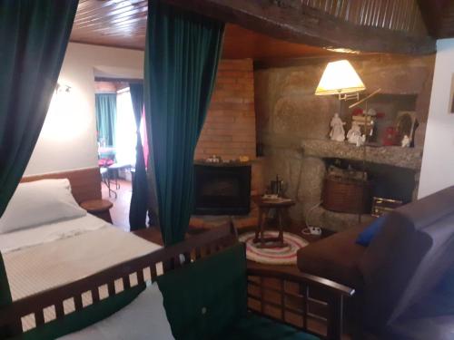 a bedroom with a bed and a living room with a fireplace at Casa da Avó Maria na Quinta do Castro in Manhuncelos