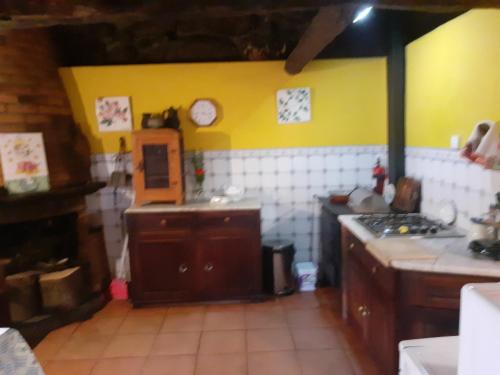 a kitchen with yellow and white tiled walls at Casa da Avó Maria na Quinta do Castro in Manhuncelos
