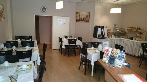 a dining room with white tables and chairs and a kitchen at City Hotel Gotland in Berlin