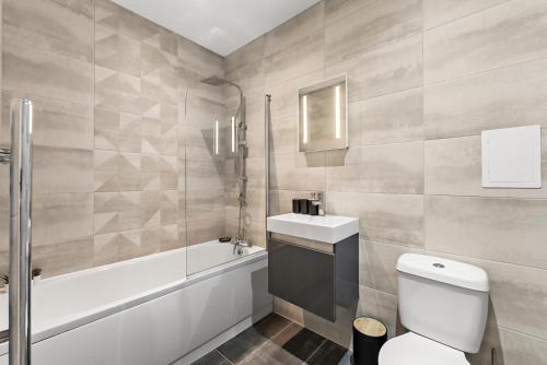 a bathroom with a toilet and a sink and a tub at Comfortable 2-Bedroom Stay in Norwich in Norwich