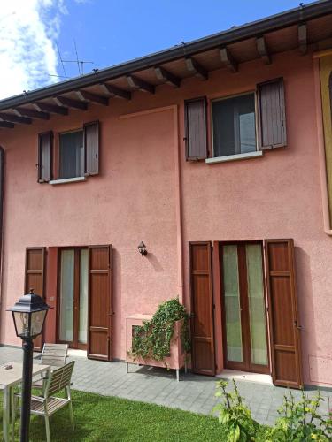 a pink house with wooden doors and a table at Omas Haus in Toscolano Maderno