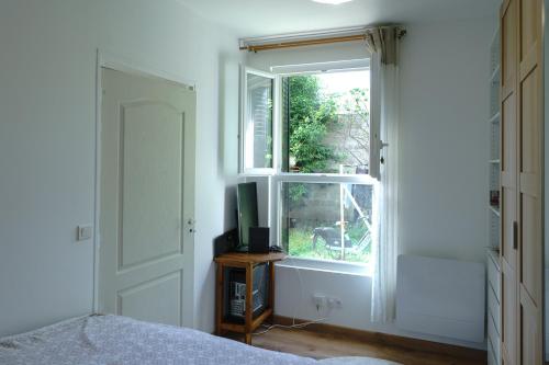 une chambre avec une fenêtre et une télévision sur une table dans l'établissement T2 Cozy sur cour - Stade de France, à Saint-Denis