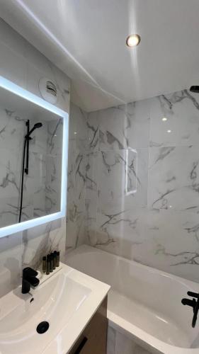 a bathroom with a tub and a sink and a mirror at H&ocirc;tel Lebron in Paris