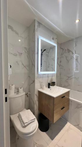 une salle de bain avec toilettes, lavabo et miroir dans l'établissement Hôtel Lebron, à Paris