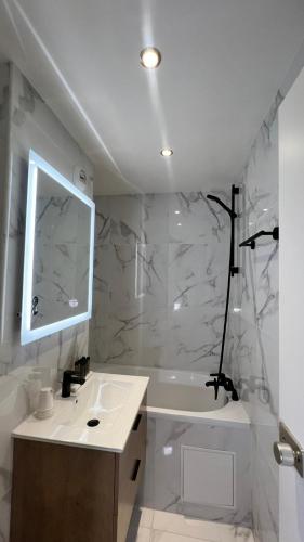 a bathroom with a sink and a mirror and a tub at H&ocirc;tel Lebron in Paris
