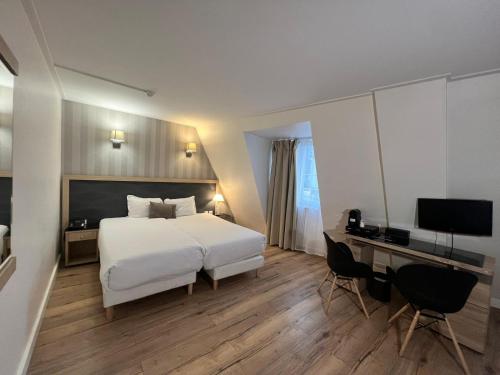 a bedroom with a bed and a desk with a computer at H&ocirc;tel Lebron in Paris
