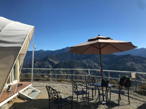 a patio with a table and chairs and an umbrella at 清境花鳥蟲鳴高山露營區 in Jen-chuang