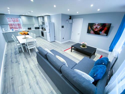 a living room with a blue couch and a kitchen at Spacious 2-Bedroom Flat in London - F3 in London