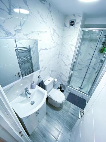 a white bathroom with a toilet and a sink at Spacious 2-Bedroom Flat in London - F3 in London