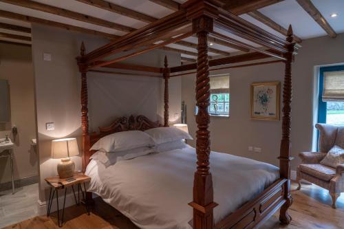 une chambre avec un lit à baldaquin et une chaise dans l'établissement Kingfisher Cottage Upperdale Peak District, à Buxton