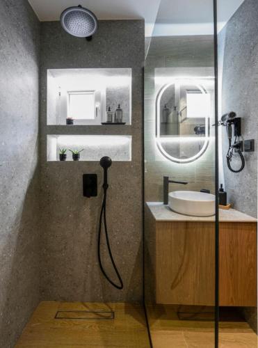 a bathroom with a glass shower with a sink at Aristotelian Virtues - Tharros in Thessaloniki