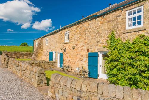 a stone house with blue doors and a stone wall at Rowsley Cottage Bakewell Peak District in Bakewell