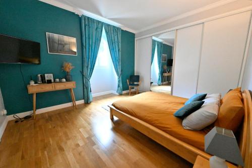 a bedroom with a large bed with blue walls at Villa MANSART in Ver-sur-Launette