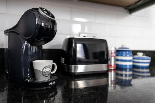 a coffee maker and a coffee cup on a counter at Regency Style Marvel Apartment 1-Bedroom Apartment in Gloucester with Parking in Gloucestershire