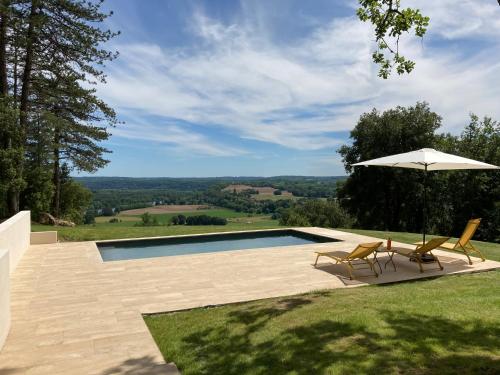 une piscine avec deux chaises et un parasol dans l'établissement LES HAUTS DE TREMOLAT, à Trémolat