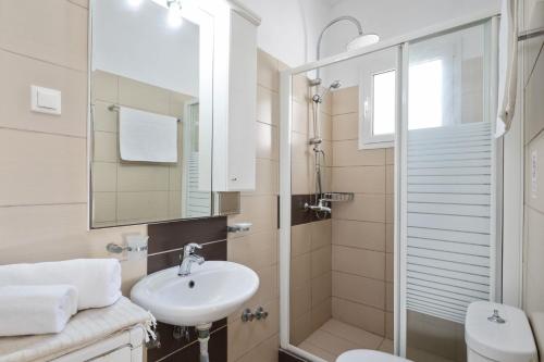 un bagno bianco con lavandino e doccia di Villa Anamari Eos Villas ad Ágios Stéfanos