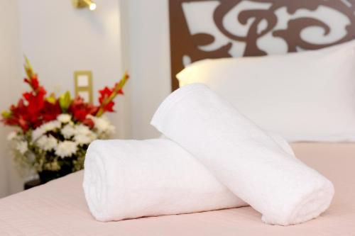 a stack of towels on a bed with a vase of flowers at Elaia-Fos in Rhodes Town