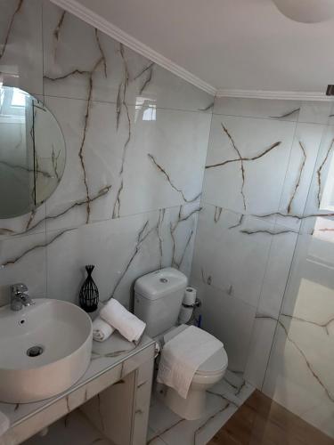 a white bathroom with a sink and a toilet at Amaya Pine Rooms in Keramotí
