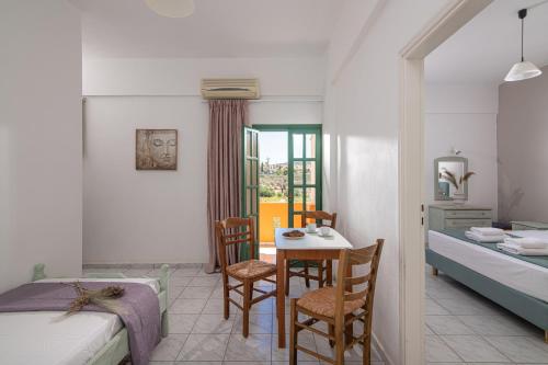 a bedroom with two beds and a table and chairs at Portokali Apartments in Hersonissos