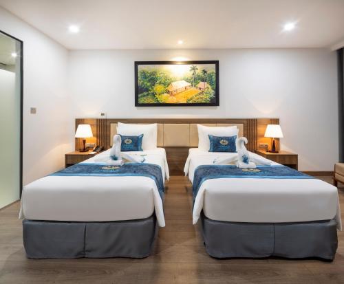two beds in a room with two lamps at Gonsala Hotel Nha Trang in Nha Trang