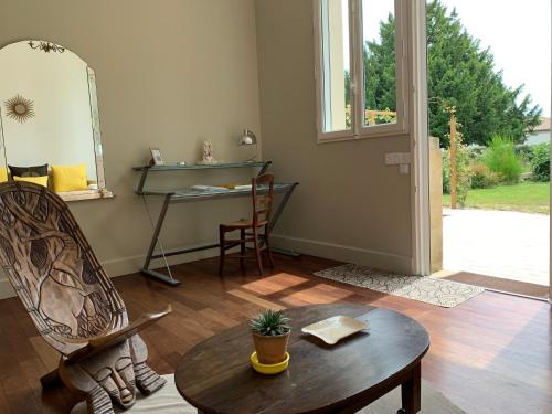 a living room with a chair and a table and a mirror at Suite privative Abella - Aile de maison bourgeoise in Ambarès-et-Lagrave