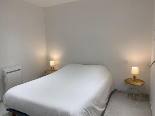 ein Schlafzimmer mit einem weißen Bett und zwei Lampen auf Tischen in der Unterkunft La Plage in Donville-les-Bains