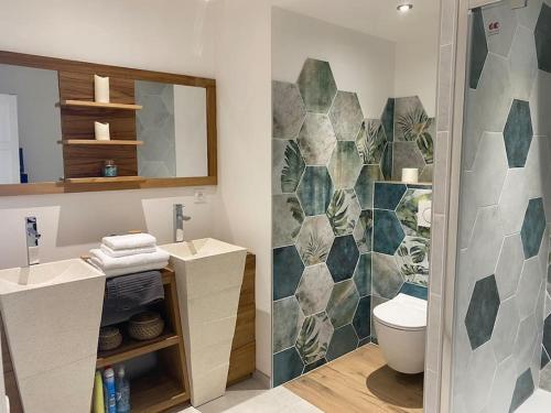 ein Badezimmer mit zwei Waschbecken und einer Toilette und einem Spiegel in der Unterkunft La Plage in Donville-les-Bains