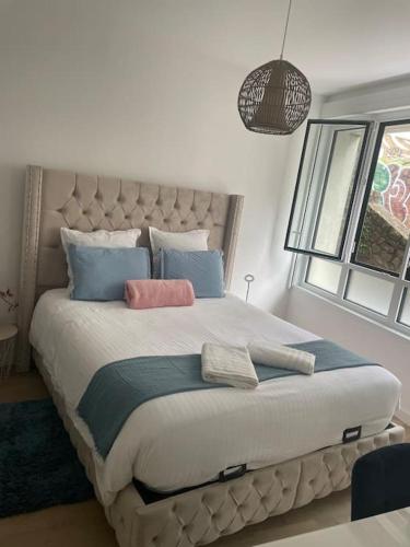 - une chambre dotée d'un grand lit avec des oreillers bleus et roses dans l'établissement Chez Hélène T2 à Nantes Centre, à Nantes