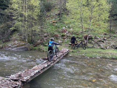 two people on bikes crossing a bridge over a river at Hotel Valls Valira in Os de Civís