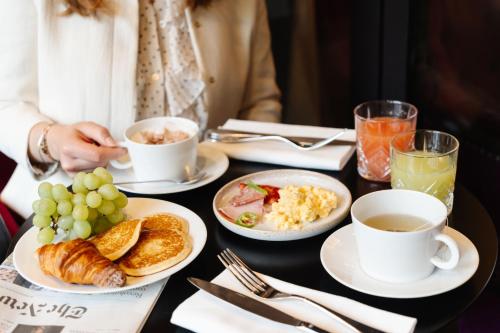 a table topped with plates of food and cups of coffee at La Villa Haussmann in Paris