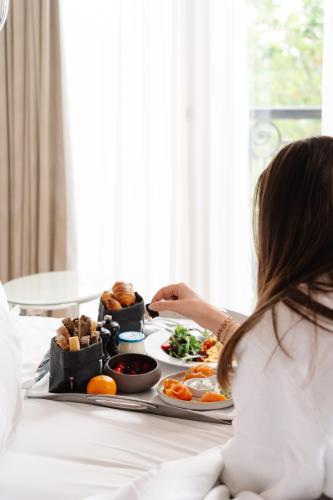 a woman sitting in bed with a tray of food at La Villa Haussmann in Paris