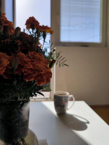 a vase of flowers and a cup on a table at Apartman Zlatija in Bajina Bašta
