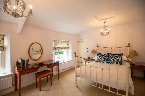 a bedroom with a bed and a desk and a mirror at Ball Cross Farmhouse Bakewell Peak District in Bakewell