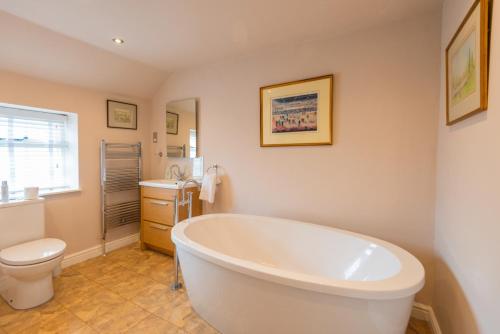 a bathroom with a tub and a toilet and a sink at Ball Cross Farmhouse Bakewell Peak District in Bakewell