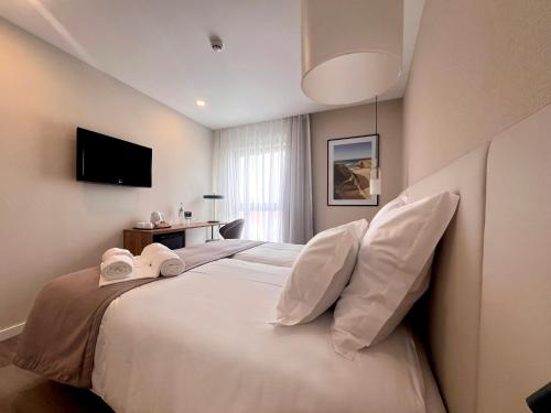 a bedroom with a large white bed with two pillows at AP Sines - Costa Alentejana in Sines