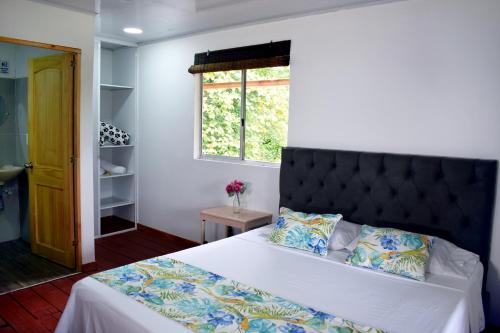 a bedroom with a bed with a black headboard and a window at Finca Hotel el Edén del Quindío in Calarcá