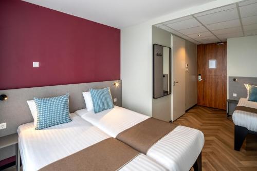 a bedroom with two beds and a red wall at Hotel Fogo Amsterdam in Amsterdam