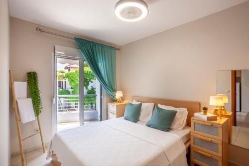 a bedroom with a bed with blue pillows and a window at Cute apartment 20m from beach in Nea Potidaea