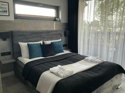 a bedroom with a large bed with blue pillows and a window at Apartamenty BLUE BALTIC SPA Jacuzzi & Sauna MORZE in Chłopy
