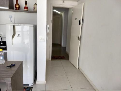 a kitchen with a white refrigerator and a hallway at Studio Espaço Moderno in Curitiba