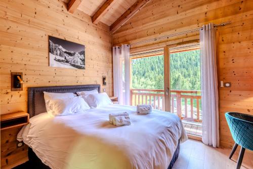 une chambre avec un lit et une grande fenêtre dans l'établissement CHALET LES EVES, à Morzine