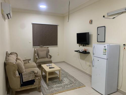 a living room with a refrigerator and chairs and a table at شقق ضيافه خاصه 5391 in Yanbu