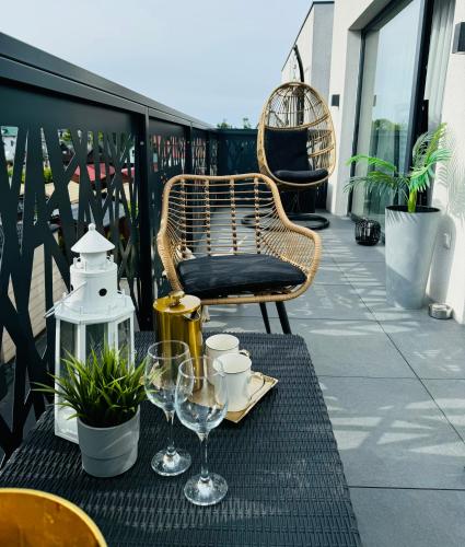 a table with a chair and wine glasses on a balcony at Apartamenty BLUE BALTIC SPA Jacuzzi & Sauna MORZE in Chłopy