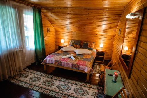 a woman laying on a bed in a wooden room at Vila Riki in Borsec