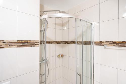 a shower in a bathroom with white tiles at Montreux Four Bedroom Penthouse by Swiss Hotel Apartments in Montreux