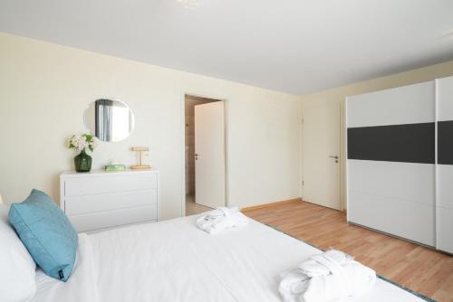 a white bedroom with a large white bed with blue pillows at Montreux Four Bedroom Penthouse by Swiss Hotel Apartments in Montreux