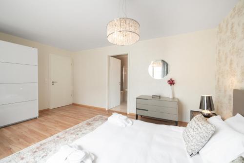 a white bedroom with a white bed and a dresser at Montreux Four Bedroom Penthouse by Swiss Hotel Apartments in Montreux