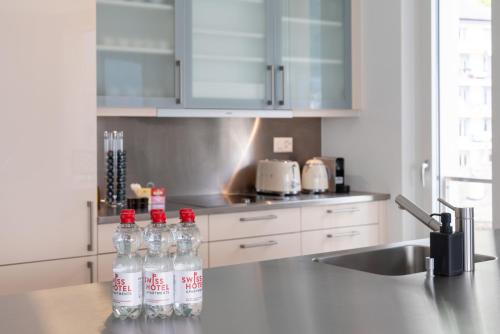 a kitchen with bottles of water on a counter at Montreux Lake View Apartments and Spa - Swiss Hotel Apartments in Montreux