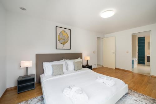a large white bedroom with a large white bed at Montreux Lake View Apartments and Spa - Swiss Hotel Apartments in Montreux